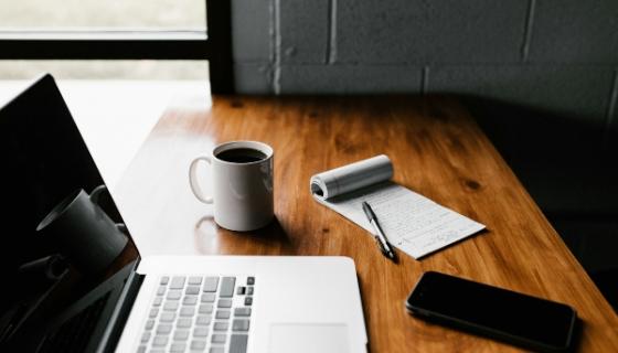 Computer, phone, notebook and coffee on a desk