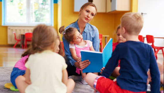 educator sitting with a group of children and reading a book