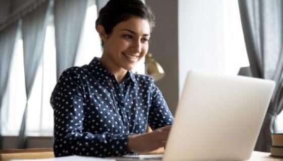 woman sitting at table working on laptop