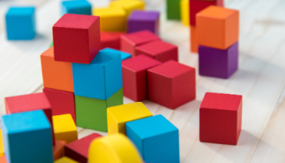 Coloured building blocks on pale wood background