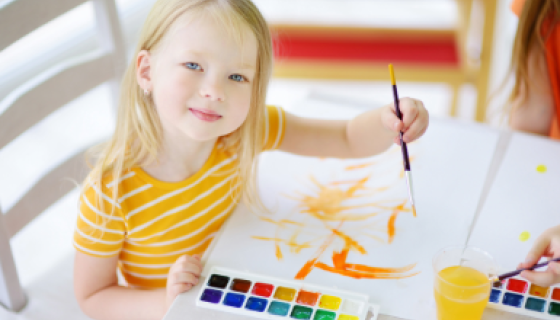 Girl sitting at a table painting with watercolours