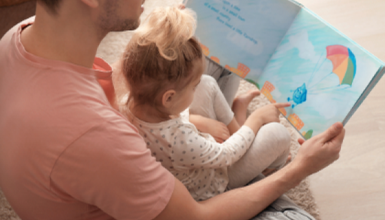 A father reading a picture book to his daughter