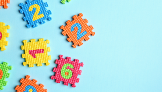 Coloured foam puzzle tiles with different numbers on them, on a plain light blue background