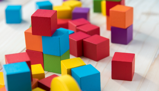 Coloured building blocks on pale wood background