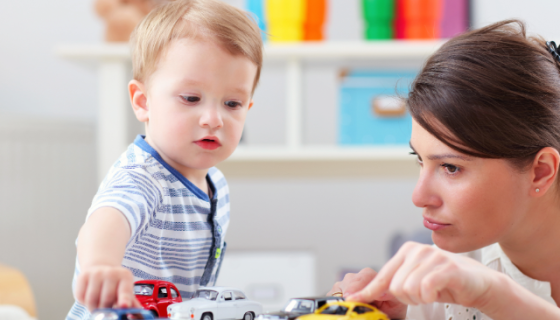 an educator and a boy playing with toy cars on a table