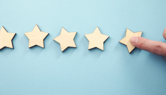 5 wooden star tiles with a finger touching the one on the most right, on a pale blue background