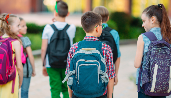 An image showing children with back packs walking away.