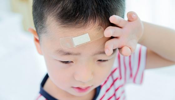 Boy with bandaid on his head looking sad