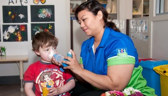 Female educator giving a boy an asthmas puffer at day care