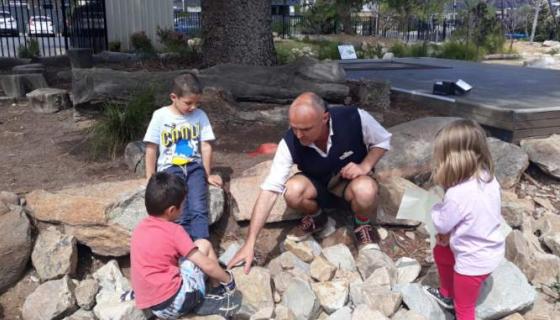 Children and teacher look for creatures among large rocks