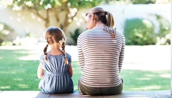 Young girl sitting with supportive woman, both facing away from our view